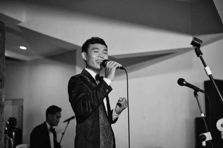 Singer in a formal suit performing into a microphone onstage